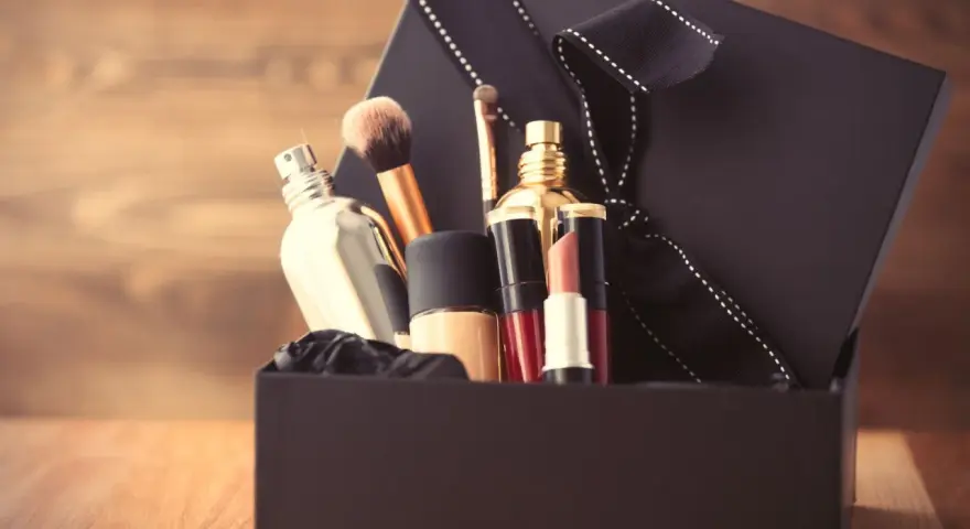 Schwarze Geschenkbox mit Kosmetikartikeln wie Parfüm, Lippenstift und Make-up-Pinseln.